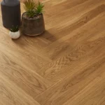 Close-up of oak herringbone floor with potted plants.