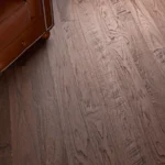 Dark wood flooring next to a brown leather armchair
