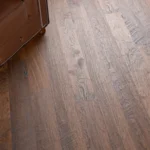 Dark wood flooring next to a leather armchair