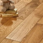 Teddy bear on books over light oak wood flooring