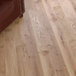 Top-down view of light oak planks and leather chair