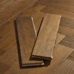 Two oak herringbone flooring samples on a wood floor.