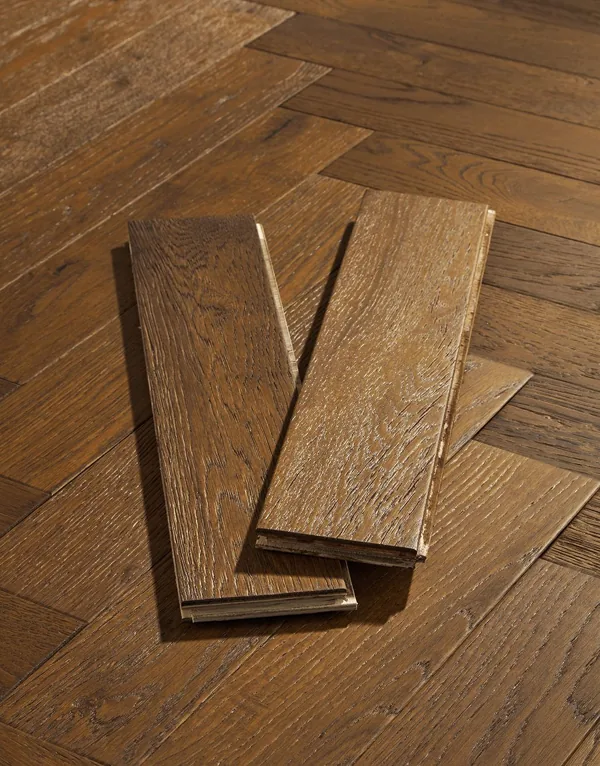 Two oak herringbone flooring samples on a wood floor.