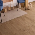 Wide view of oak flooring under chairs and a rug