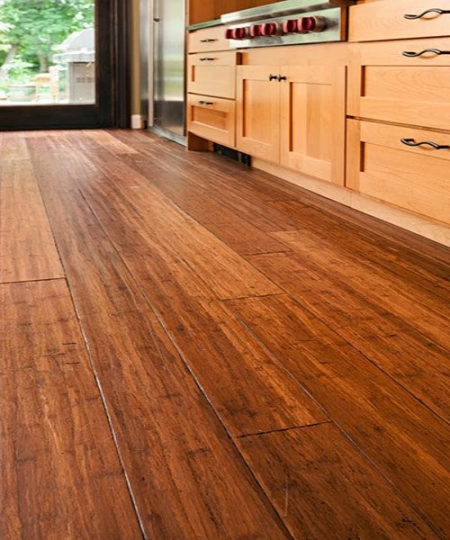 Rustic cherry wooden flooring in a kitchen with light wood cabinetry.